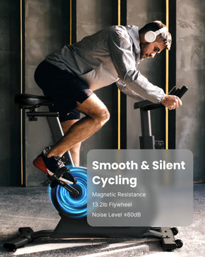 A man wearing a grey jacket and headphones exercises on the Renpho AU AI Smart Bike S in a dimly lit room. Text overlay on the image reads, "Smooth & Silent Cycling. Magnetic Resistance. 13.2lb Flywheel. Noise Level ≤60dB." Highlighted with a blue circular graphic, the bike offers an immersive fitness experience like no other.